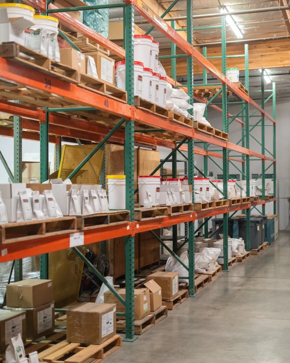 Orsetti Seeds warehouse — numbered lot storage racks with packaged seed bags and buckets in organized positions